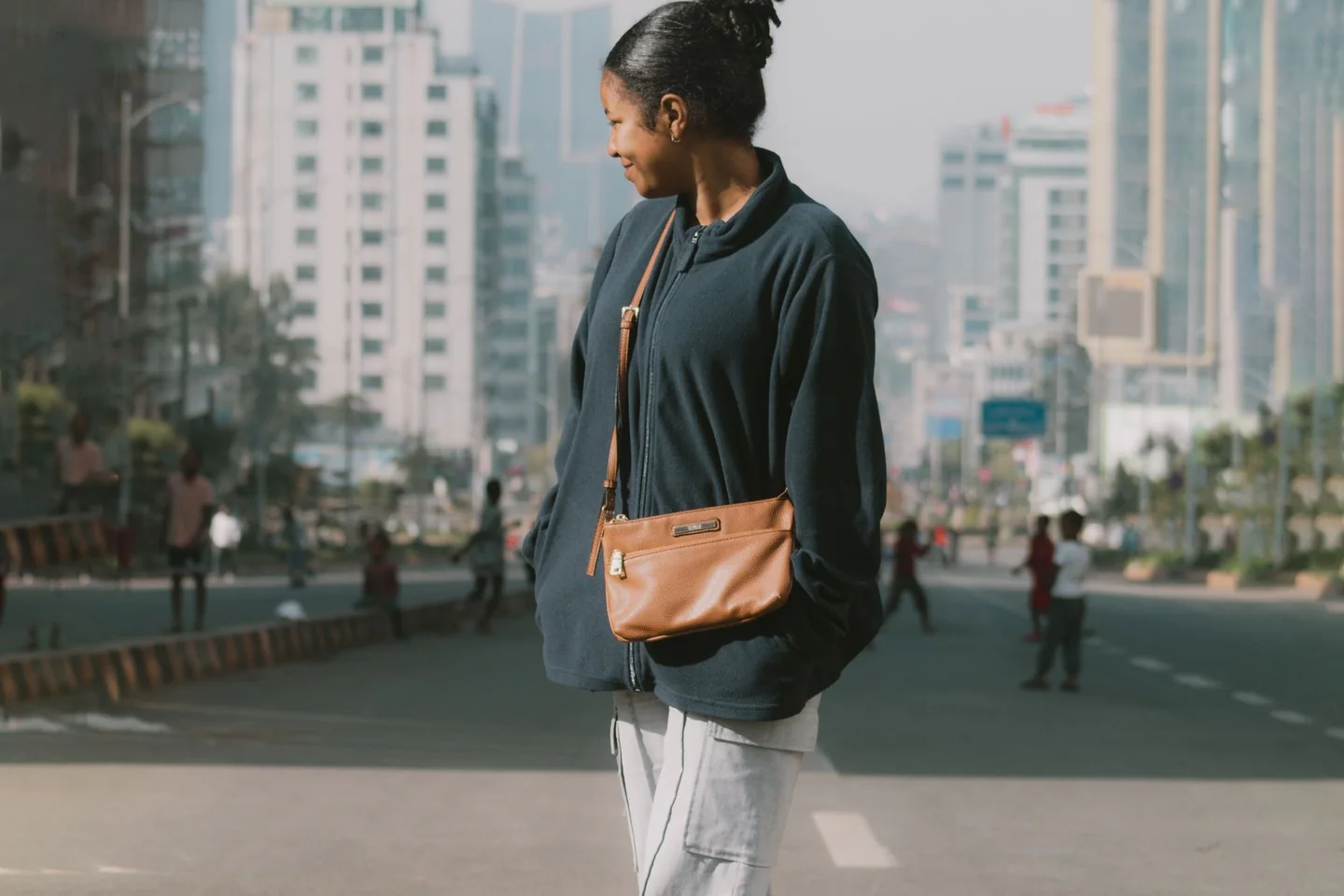 Candid city lifestyle image of a woman converting a structured shoulder bag from crossbody for lunch to short strap for dinner